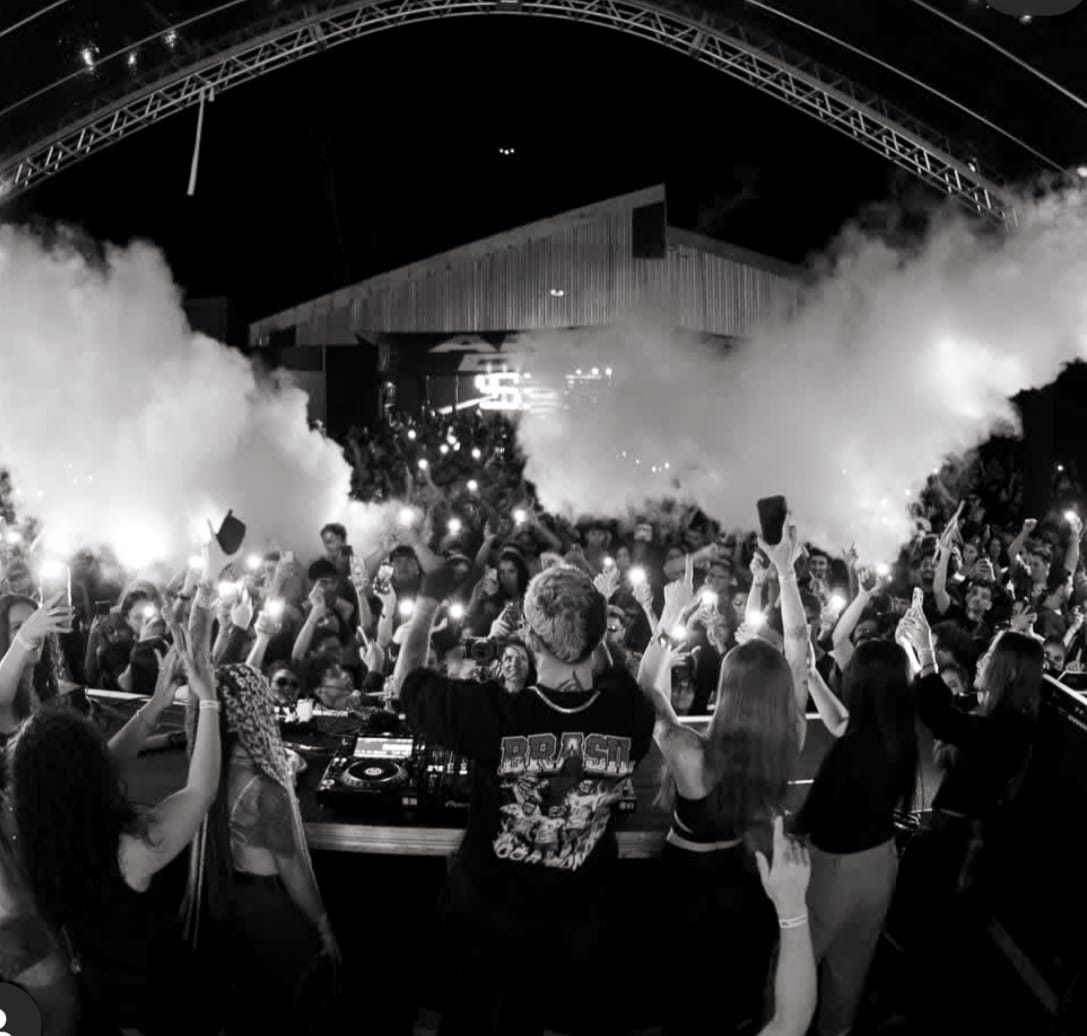 DJ Noobreak no palco com fumaça e plateia iluminada