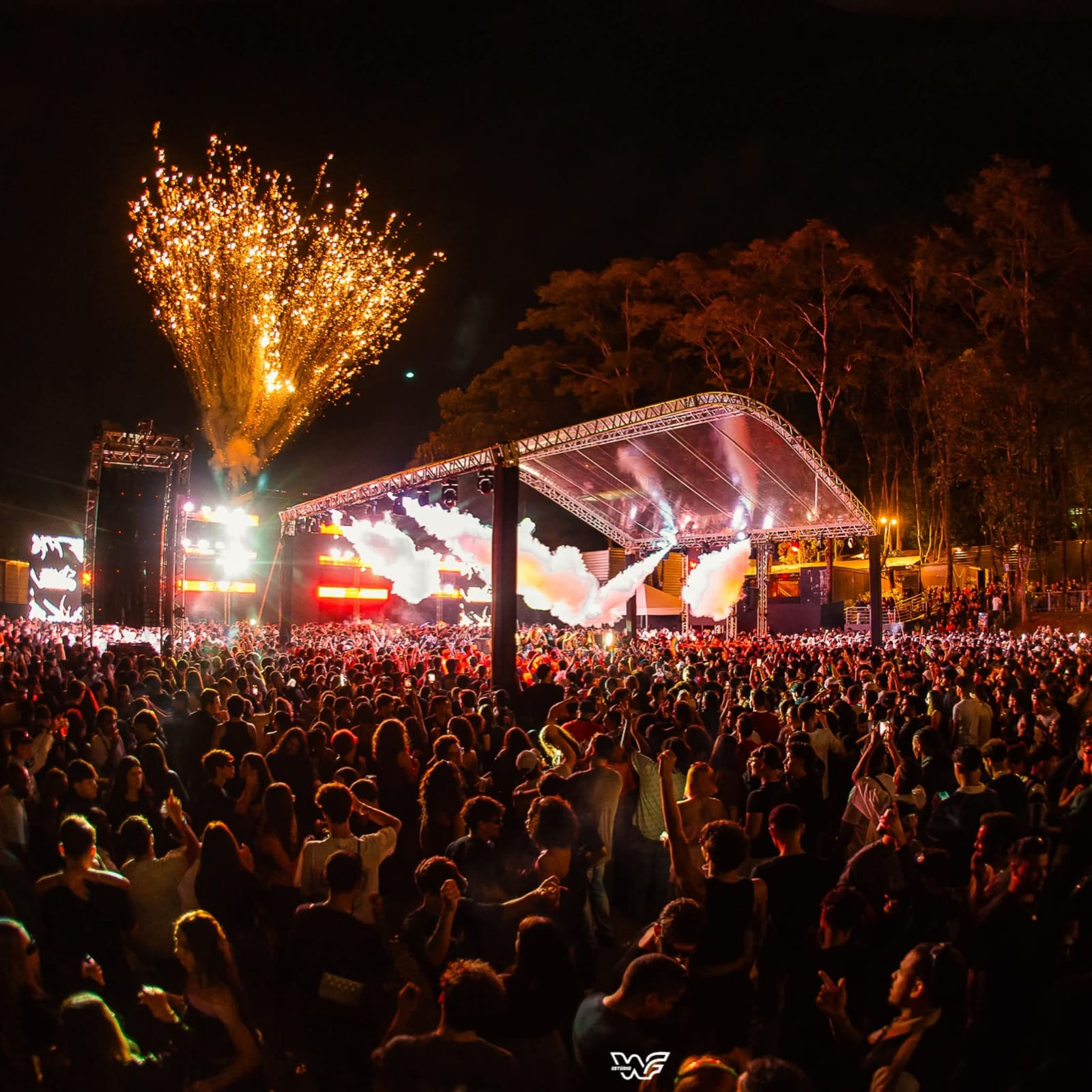 Show noturno lotado com fogos, fumaça e iluminação intensa
